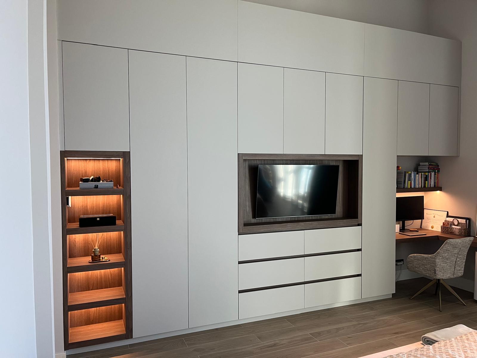 Complete kastenwand met inloopkast en werkruimte Deze kastenwand op maat is door Meubelmaker Hirsch volledig ontworpen en vervaardigd naar de wensen van de klant. De maatwerkkast combineert een strak wit design met een warme houtkleur en biedt een slimme indeling met veel opbergruimte.</p>
<p>De kastenwand is voorzien van een vitrinekast met ingebouwde verlichting, een ingebouwde tv, een praktische werkplek op maat en diverse opbergmogelijkheden. Aansluitend is een ruime inloopkast op maat gerealiseerd in houtkleur, waardoor een stijlvolle en functionele verbinding ontstaat tussen wonen, werken en opbergen.